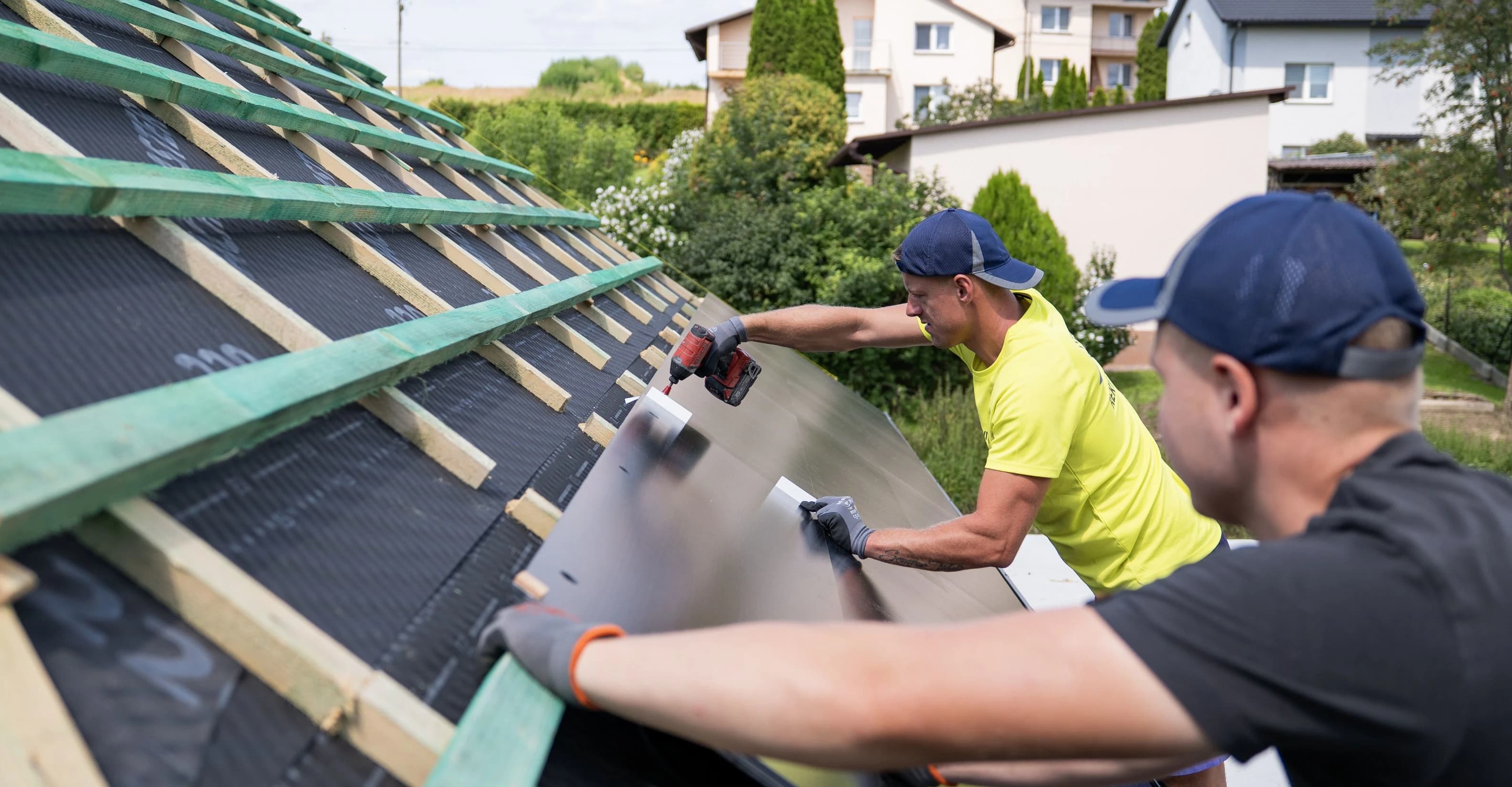Modernes Haus mit großem geneigtem Dach vor einem Waldhintergrund.