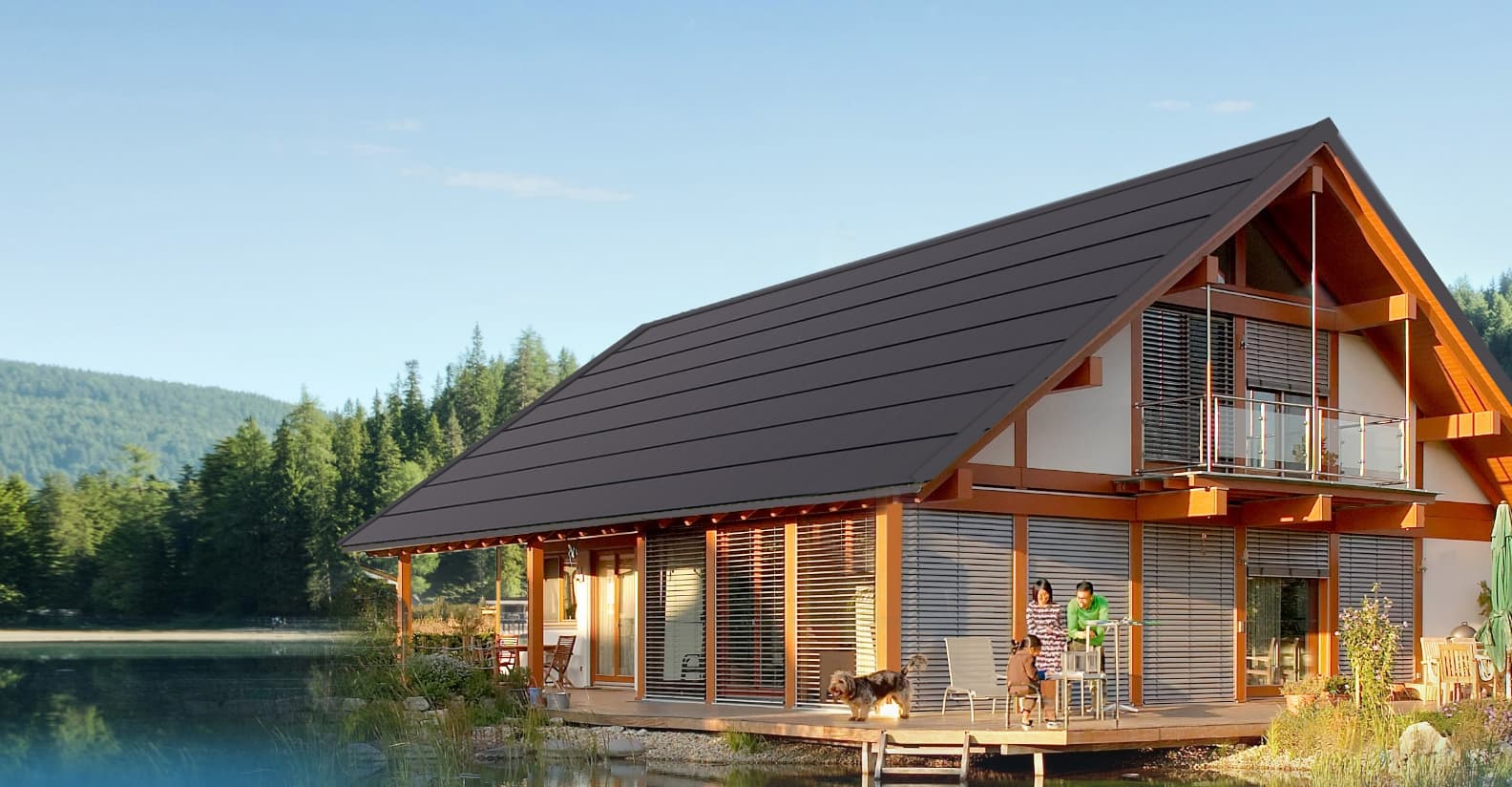 A modern house with a large sloped roof set against a forest backdrop.