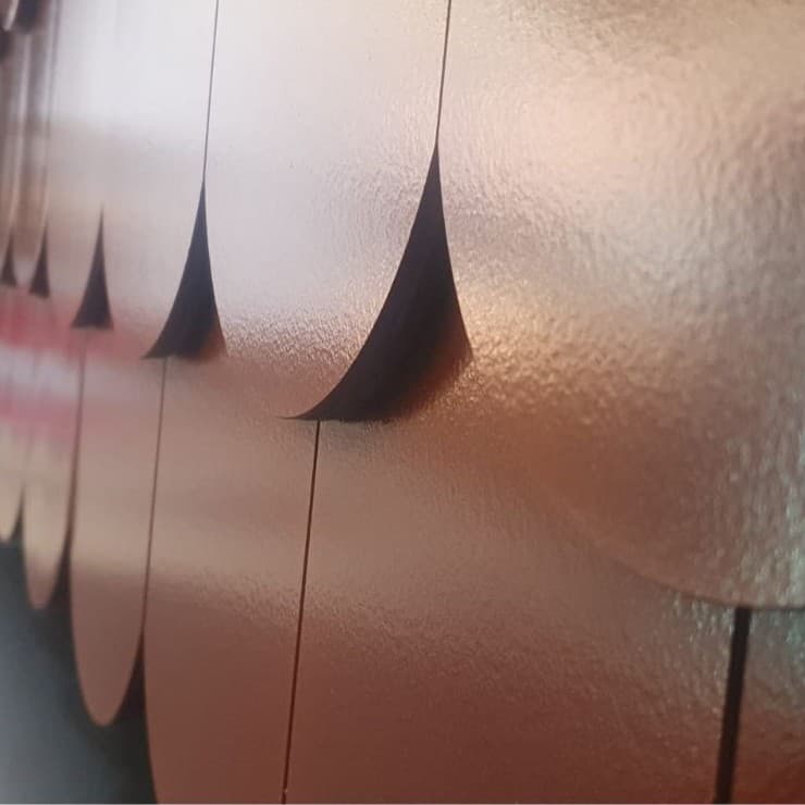 Zbliżenie na połyskującą powierzchnię, gdzie widać dekoracyjnie ułożone dachówki solarne o zaokrąglonym kształcie