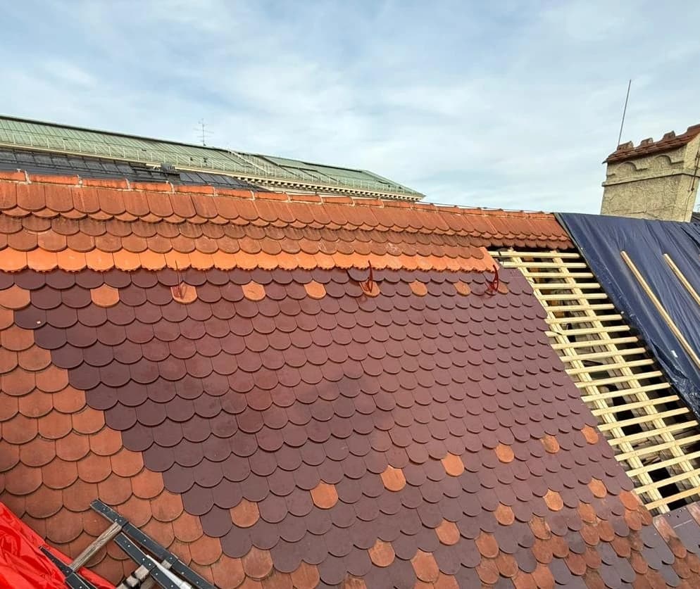 A sloped roof under renovation with fish-scale clay tiles