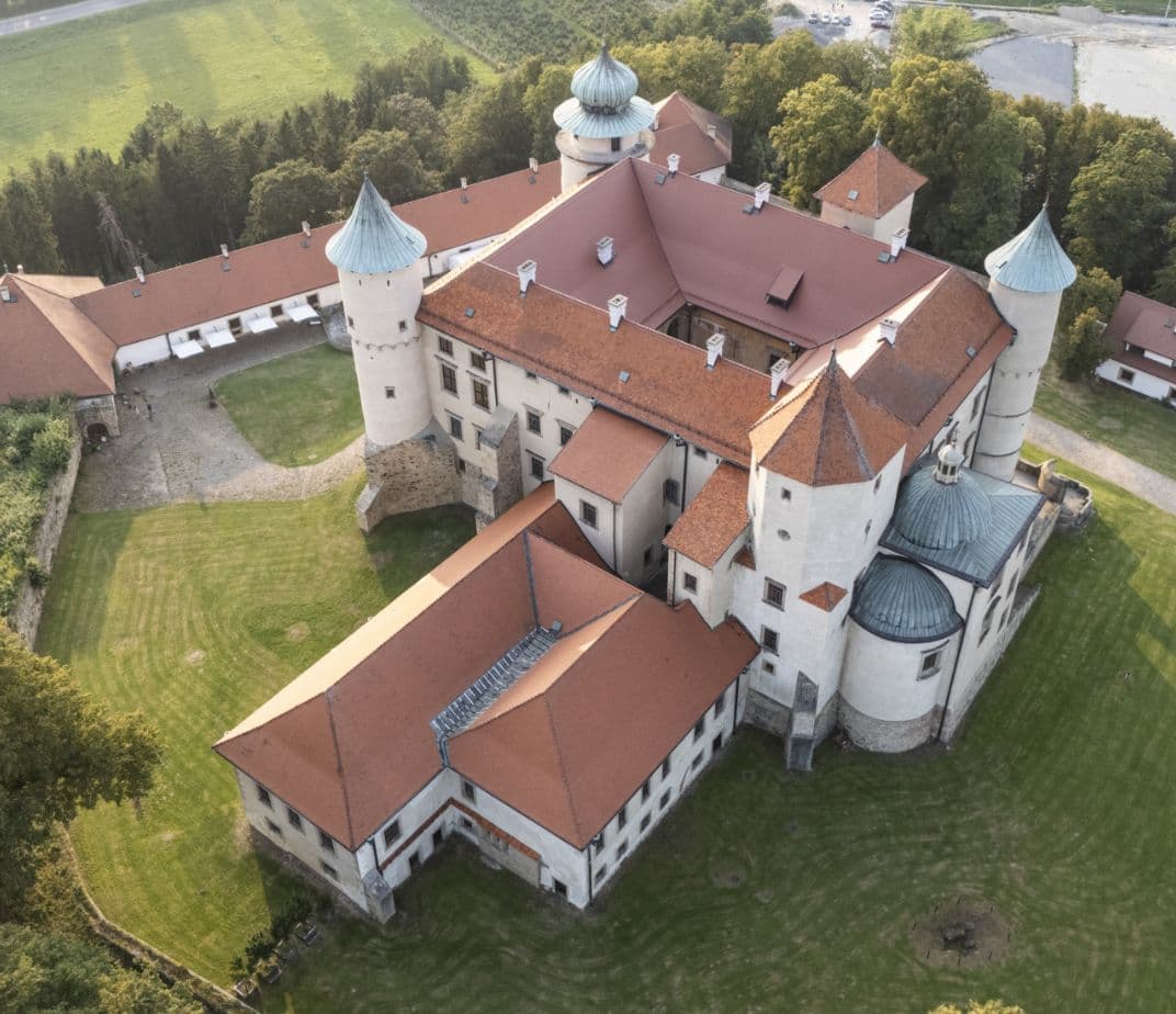Aerial view of Wiśnicz Castle surrounded by manicured lawns and trees