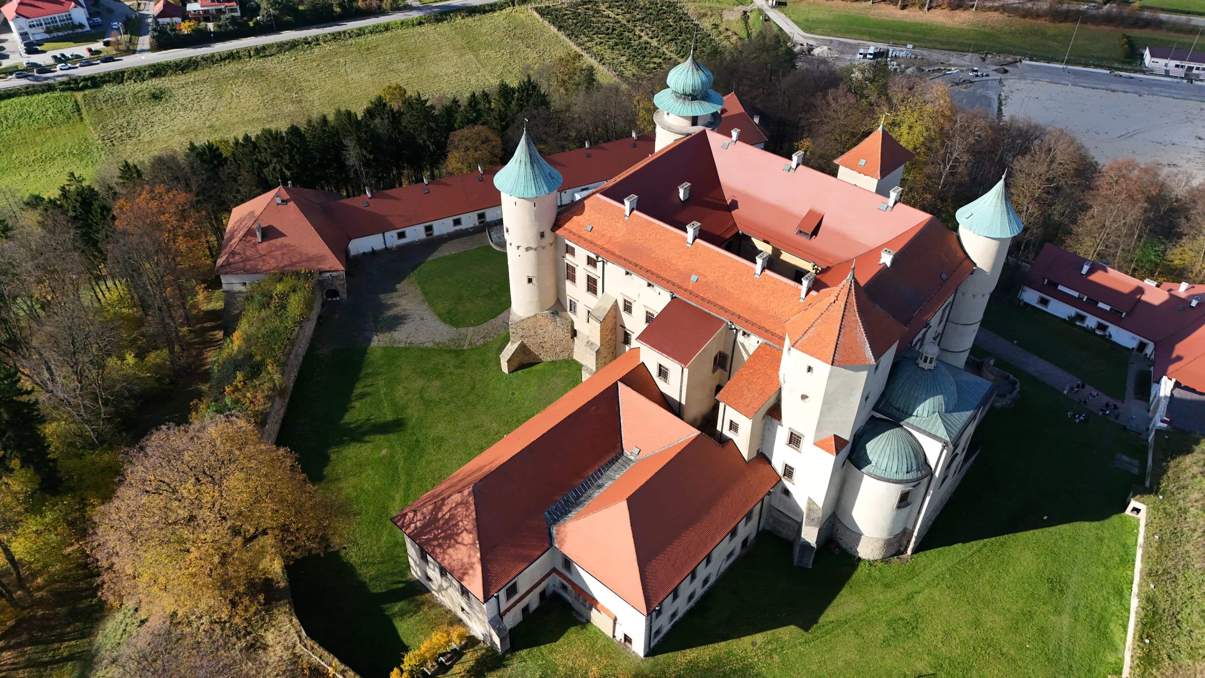 Aerial view of the Wiśnicz Castle complex surrounded by green lawns and trees