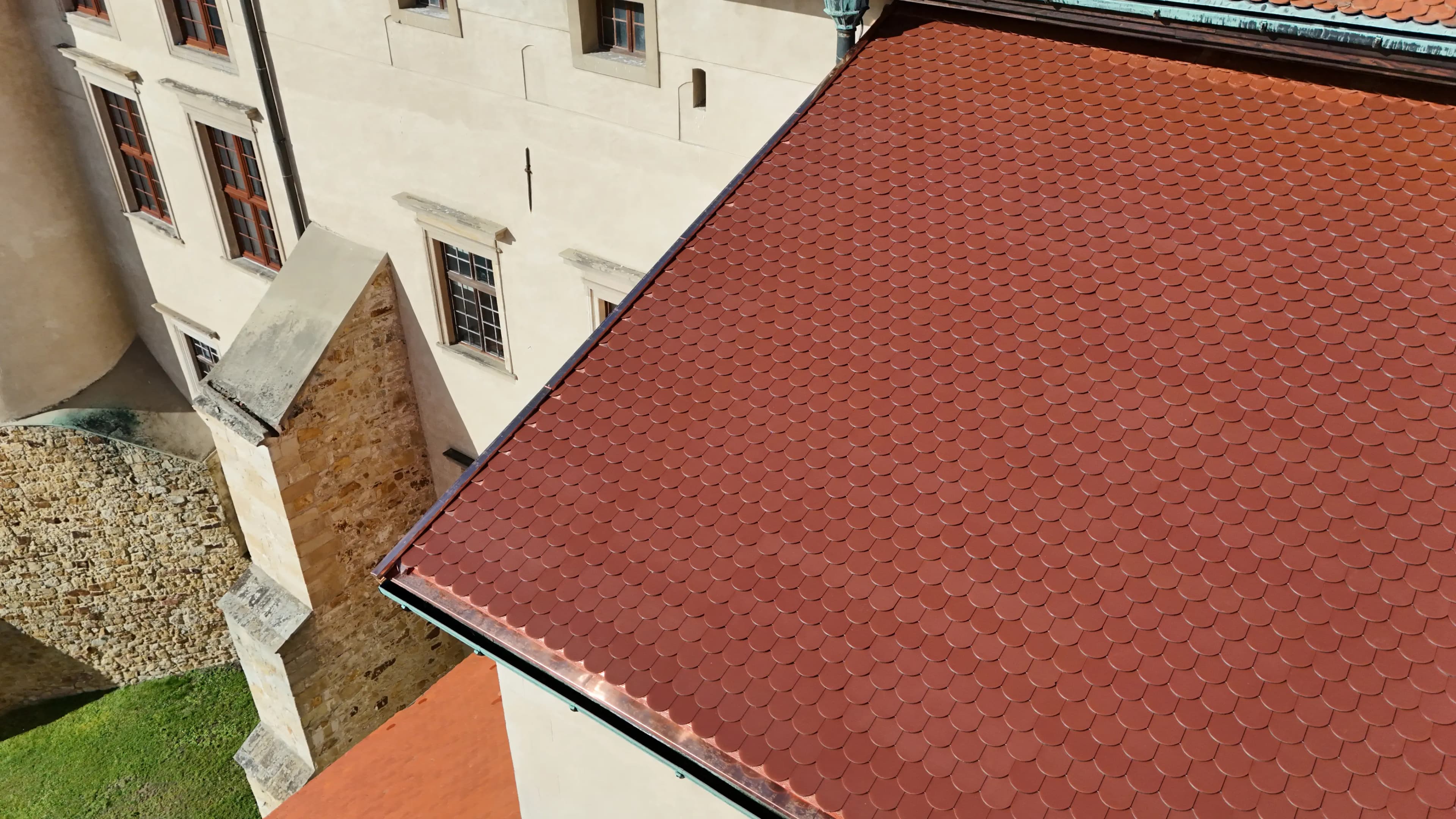 Close-up aerial view of Wiśnicz Castle’s renovated red fish-scale tile roof
